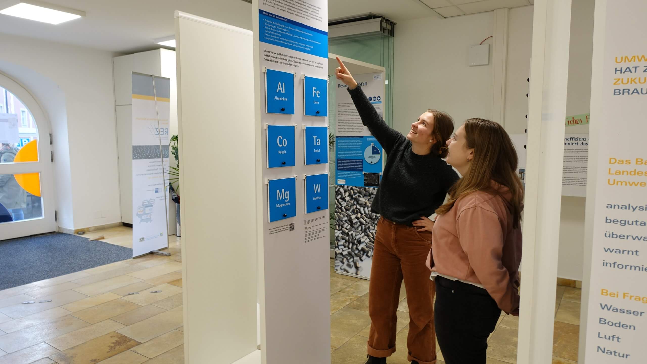 Zwei Studentinnen sehen sich die Ausstellung "Ressourceneffizienz - weniger ist mehr" an.