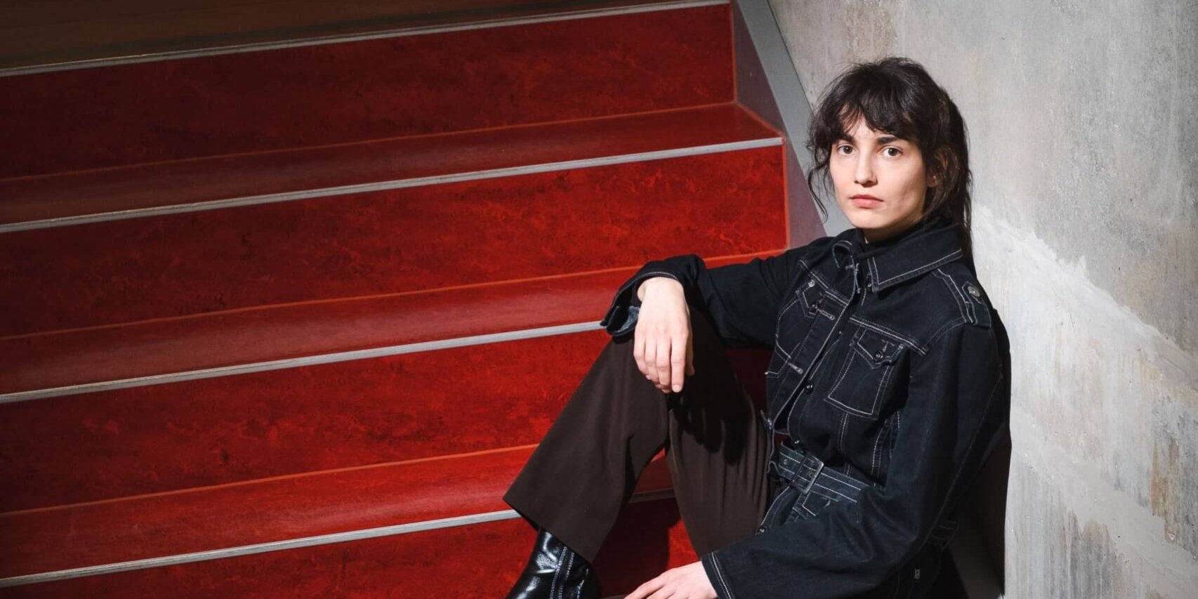 Jenifer Becker_Fotoverweis_Franziska Gilli Die Wissenschaftlerin und Autorin Jenifer Becker sitzt auf einer roten Treppe.