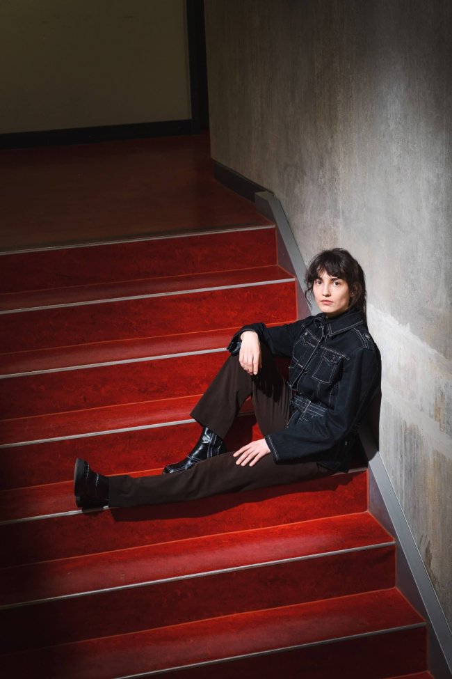 Jenifer Becker_Fotoverweis_Franziska Gilli Die Wissenschaftlerin und Autorin Jenifer Becker sitzt auf einer roten Treppe.