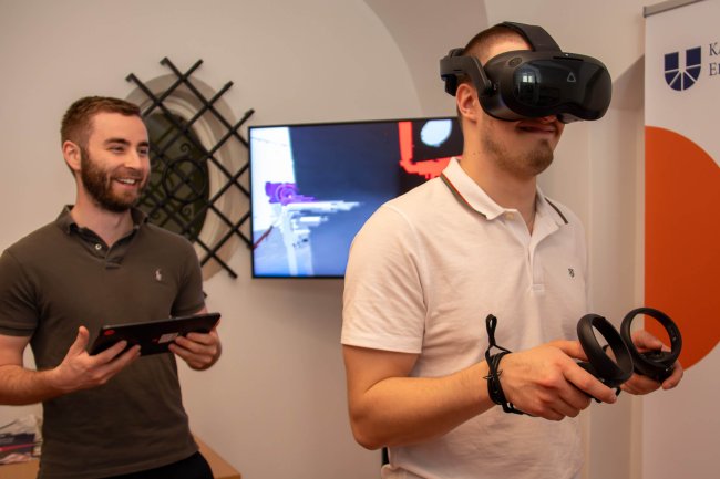 VR-Raum bei I AM AI_Foto_Laura Wagner Zu sehen sind zwei junge Männer. Einer von beiden trägt eine VR.-Brille.