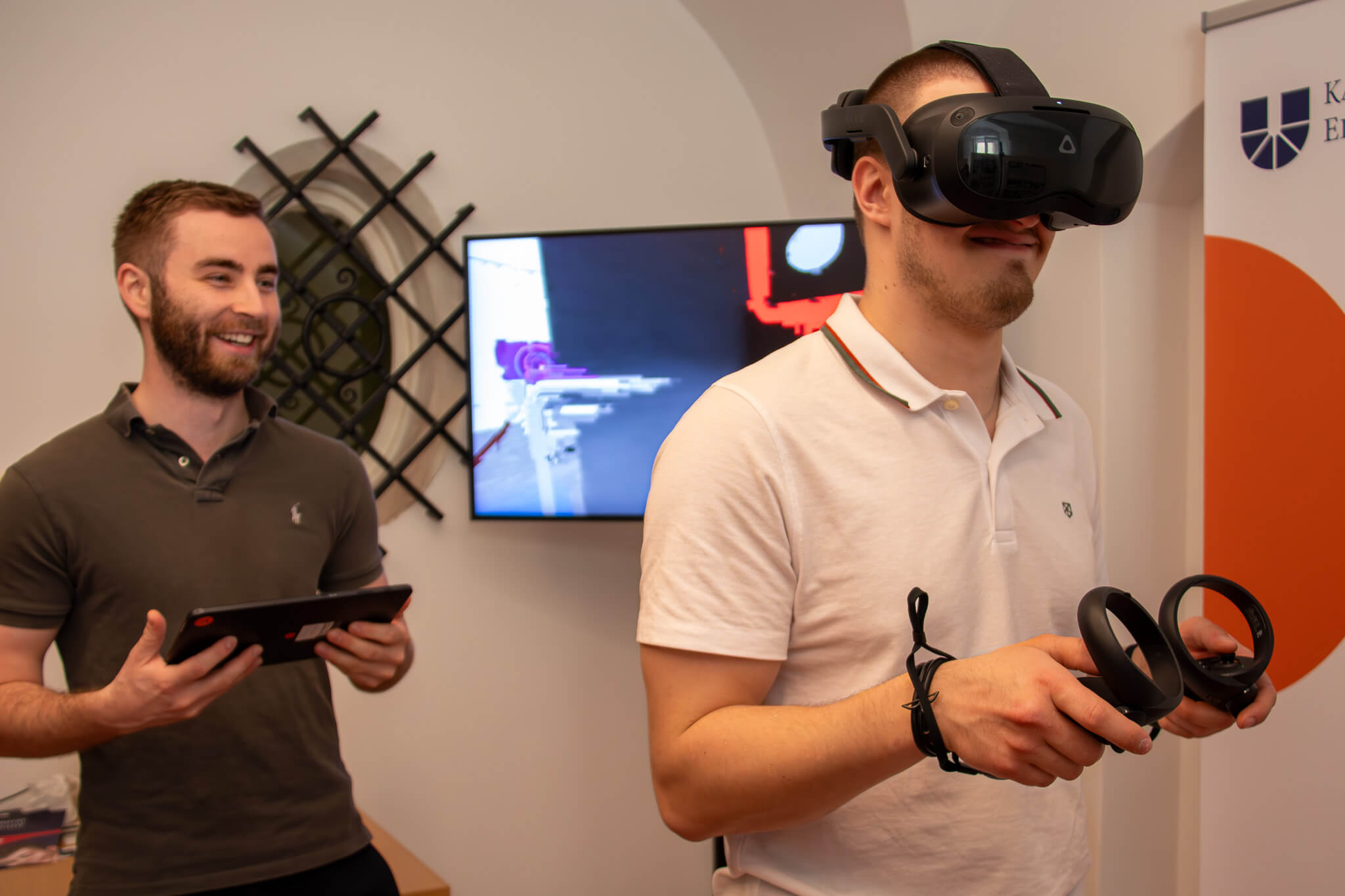 Zu sehen sind zwei junge Männer. Einer von beiden trägt eine VR.-Brille.